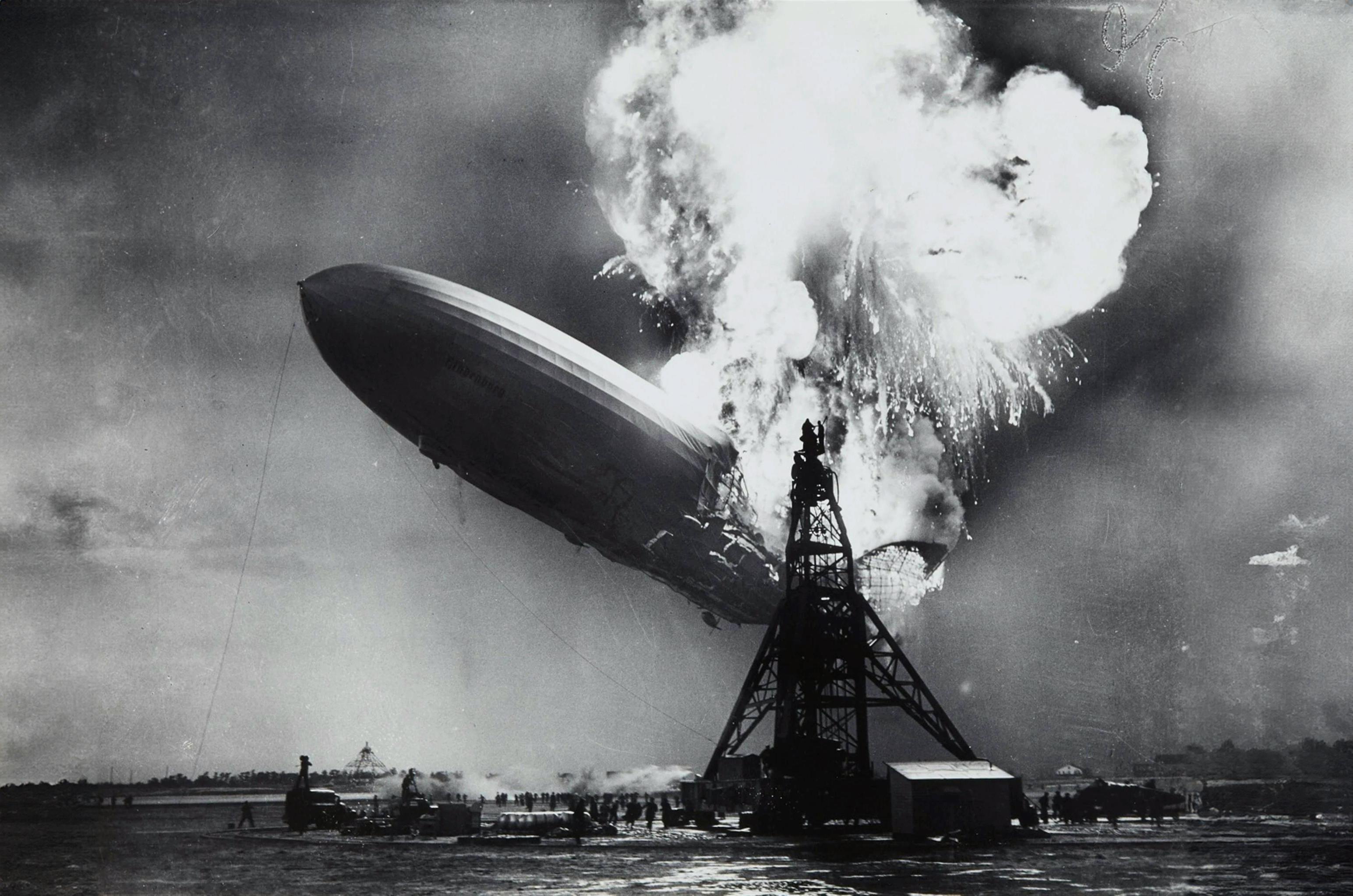 Das Foto verewigt den Moment, als das Luftschiff Hindenburg 1937 in New Jersey sein katastrophales Schicksal erlitt. Sein Absturz wurde weltweit in den Medien verbreitet und markierte das Ende des transatlantischen Luftschiffverkehrs.  - Sam Shere (1905–1982), Public domain, via Wikimedia Commons